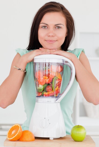 Lachende donkerharige vrouw poseren met een blender