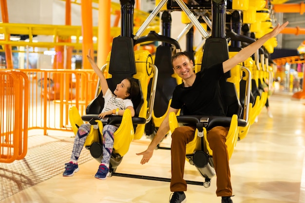 Lachende familie rijden op een achtbaan in een pretpark.