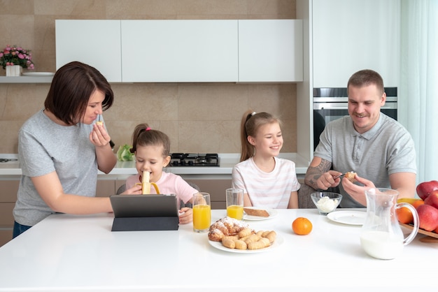 Lachende familie samen dineren aan de keukentafel en plezier, ouders met twee dochters