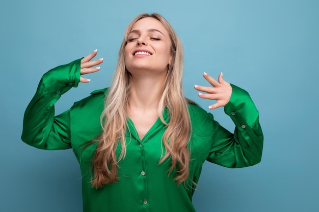 Lachende gelukkige vrouw op vakantie in groen shirt poseren op blauwe studio achtergrond