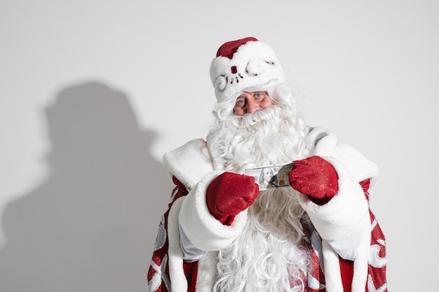 Lachende gulle Kerstman met lange witte baard in fancy kostuum bankbiljet bedrijf in handen met rode wanten.