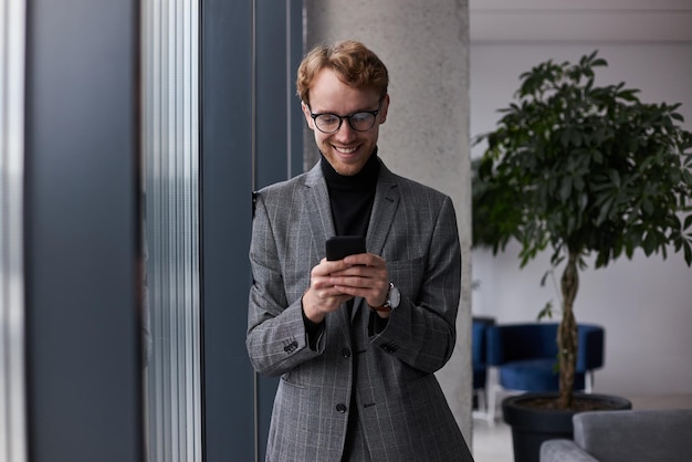 Lachende hipster man met smartphone met behulp van mobiele app, tekstbericht lezen, e-mail controleren