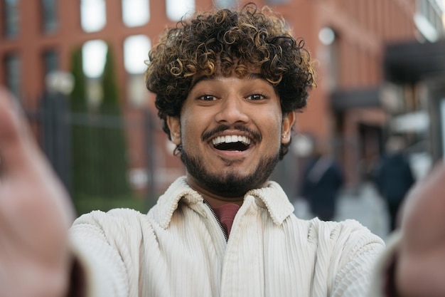 Foto lachende indiase toerist die selfie maakt, buiten een videogesprek voert