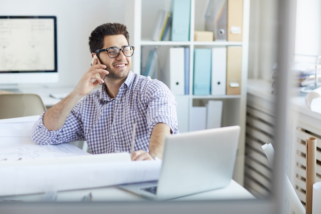 Lachende ingenieur spreken via de telefoon