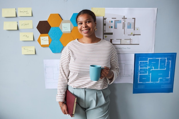 Lachende jonge architect met kopje koffie