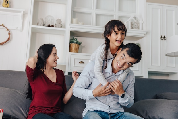 Lachende jonge Aziatische ouders en hun kind zijn erg blij, ze zijn thuis