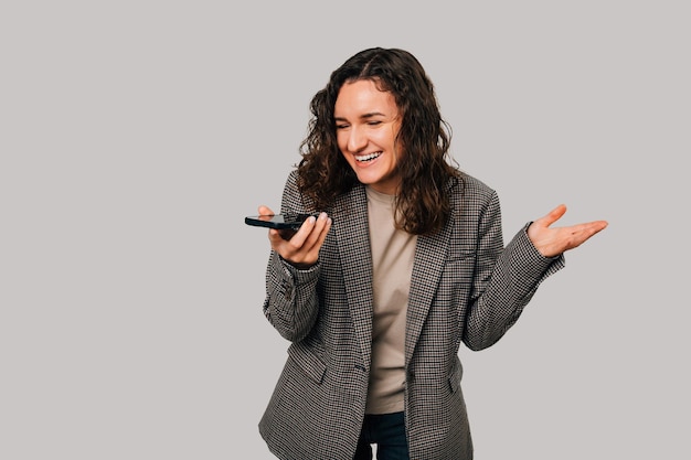 Lachende jonge krullende man heeft een grappig gesprek via haar telefoon