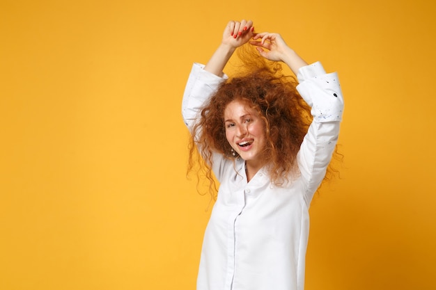 Lachende jonge roodharige vrouw meisje in wit overhemd poseren geïsoleerd op geel oranje wall