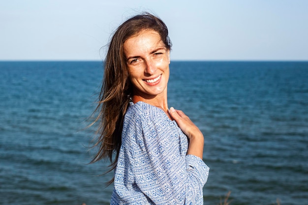 Lachende jonge vrouw in jurk op de achtergrond van de zee.