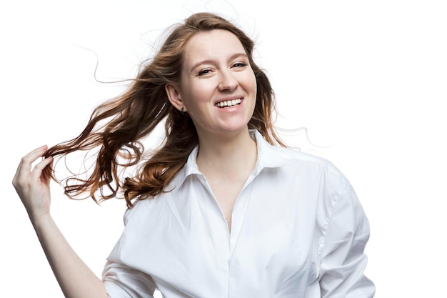 Lachende jonge vrouw met bruin lang haar in een wit overhemd Geluk en positieve witte achtergrond