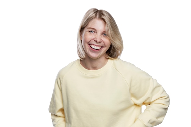 Lachende jonge vrouw. Mooie blonde in een gele trui. Geluk, positiviteit en vrijheid. Geïsoleerd op een witte achtergrond.