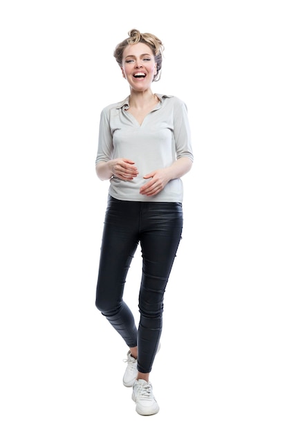 Lachende jonge vrouw staat Mooie blonde in zwarte legging grijze t-shirt en witte sneakers Positiviteit en vreugde Volledige hoogte Geïsoleerd op witte achtergrond Verticaal