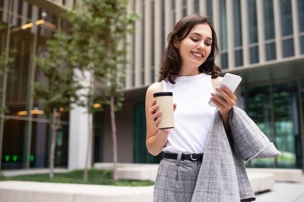 Lachende jonge zakenvrouw sms'en op smartphone buiten in het stadsgebied