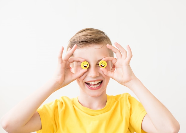 Lachende jongen die in zijn hand grappige gele smileys houdt in plaats van ogen