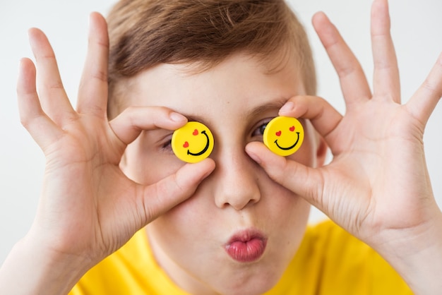 Lachende jongen die in zijn hand grappige gele smileys houdt in plaats van ogen