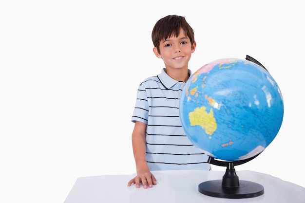 Lachende jongen poseren met een globe