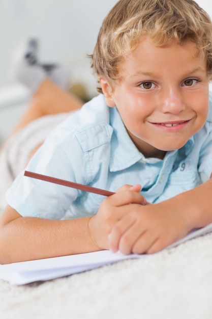 Lachende jongen schrijven op de vloer liggen