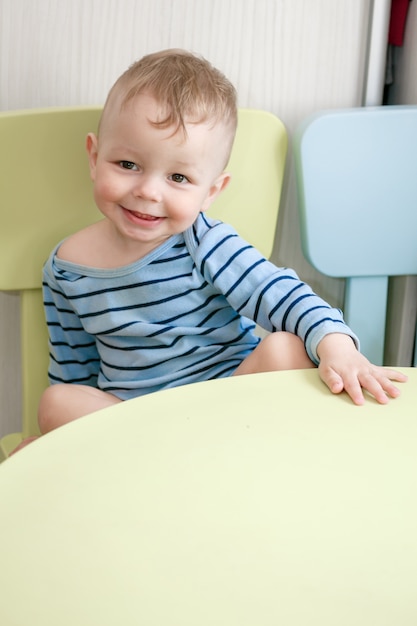 Lachende jongetje zit aan de tafel