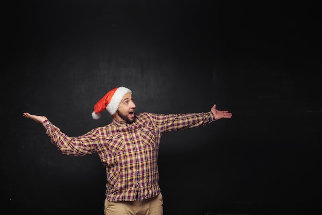 Lachende kerst man met een kerstmuts geïsoleerd op zwart