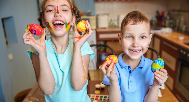 Lachende kinderen jongen en meisje tonen versierde paaseieren thuis in de keuken