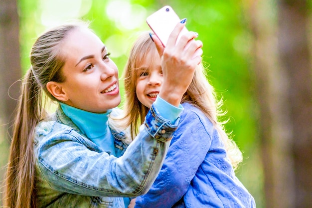 Lachende moeder en dochter maken selfie tijdens een wandeling in het bos Positieve zonnige zomerdag