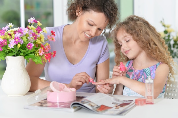 Lachende moeder met dochtertje met tijdschrift thuis