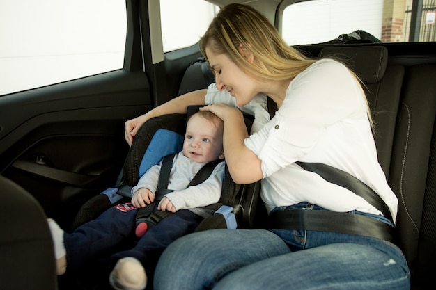 Lachende moeder zittend op de achterbank van de auto met haar baby