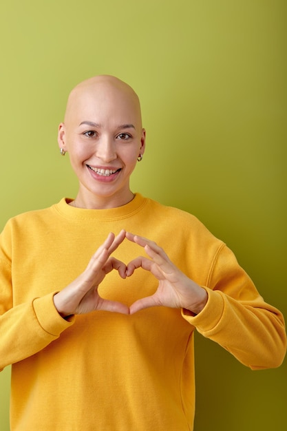 Lachende mooie blanke kale vrouw die zich voordeed op groene studio achtergrond