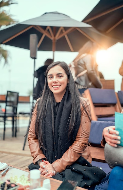 Lachende mooie Latijns-vrouw zitten in café buiten werken met collega's