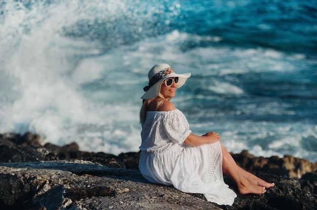Lachende mooie vrouw op het strand in een stro hoed op het eiland Zakynthos.A meisje in een witte jurk bij zonsondergang op het eiland Zakynthos, Griekenland.