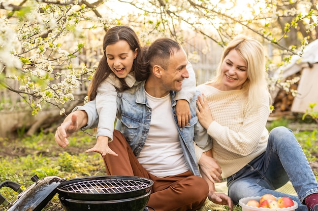 lachende ouder die vlees grilt met dochter op de camping.