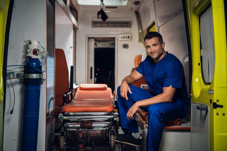Lachende paramedicus in een blauwe uniform zitten in de achterkant van een ambulance auto