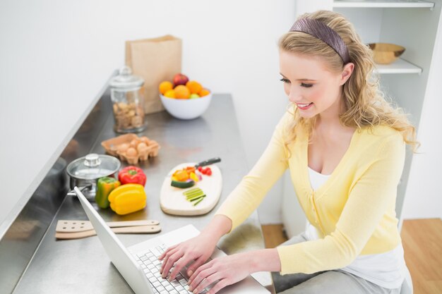 Lachende schattige blonde typen op haar laptop