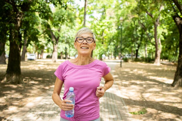 Lachende senior blanke vrouw joggen in het park.