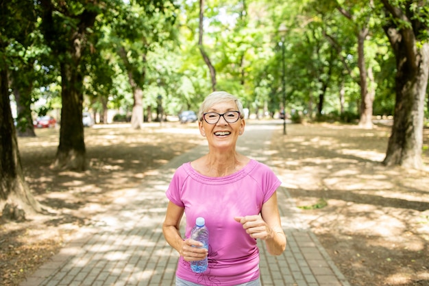 Lachende senior blanke vrouw joggen in het park.