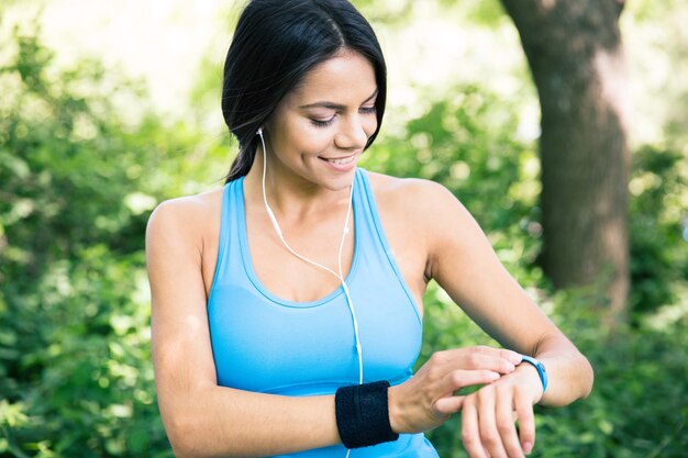 Lachende sportieve vrouw met behulp van slimme horloge buitenshuis