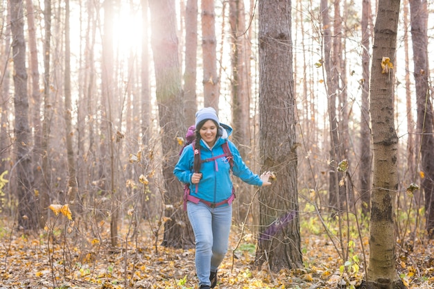 Lachende toeristische vrouw wandelen met rugzakken over herfst natuurlijke achtergrond.