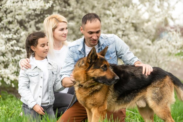 Foto lachende vader, moeder, dochter en hond spelen. zon schijnt op idyllische gelukkige familie met hond veel plezier in de achtertuin