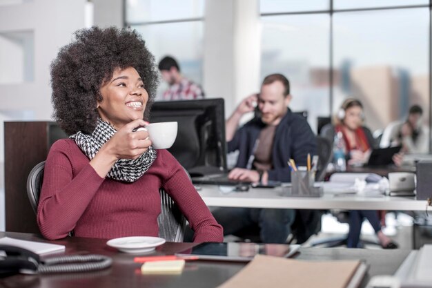 Lachende vrouw aan de balie in kantoor koffie drinken