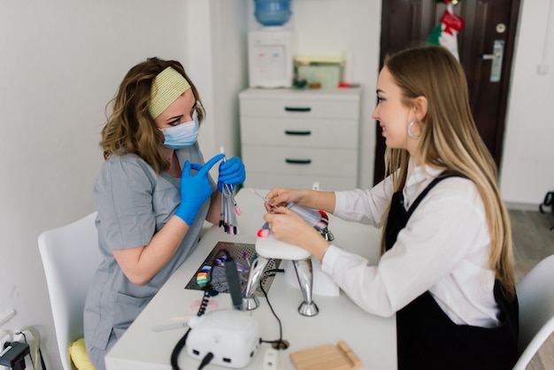 Lachende vrouw bij schoonheidssalon heeft een manicure van manicure master. Master gebruikt een nagelvijl.