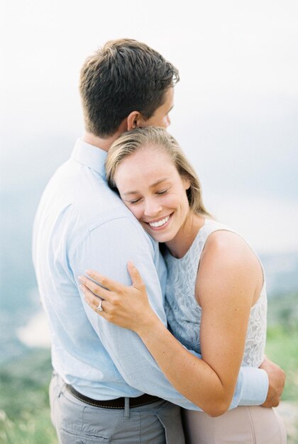 Lachende vrouw die een man omhelst terwijl hij op een berg staat Portret