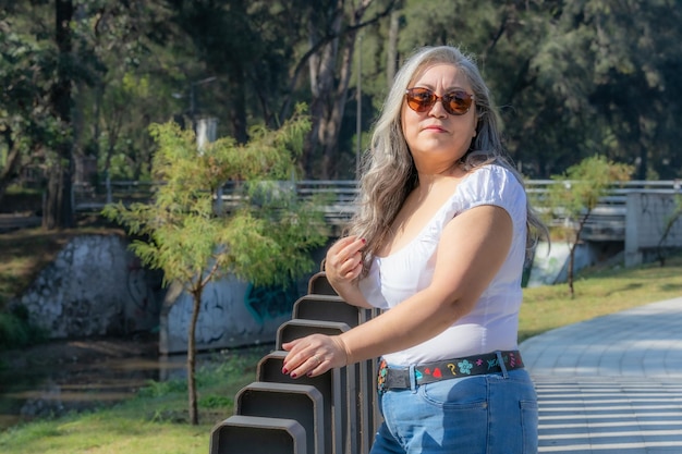 Lachende vrouw die geniet van de zonnige brugstroom en bomen met groen gebladerte in een park