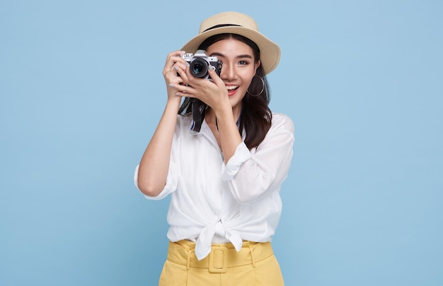 Lachende vrouw fotograaf neemt foto's foto met dslr camera geïsoleerde studio blauwe achtergrond