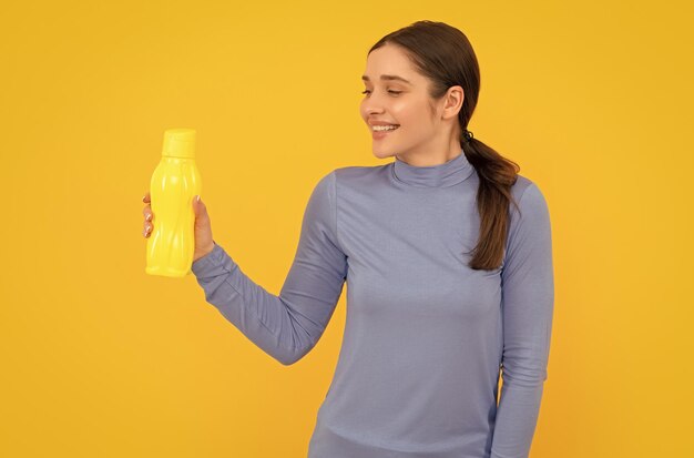 Lachende vrouw houdt mineraalwater vast en voelt dorstige jongedame met sport plastic fles