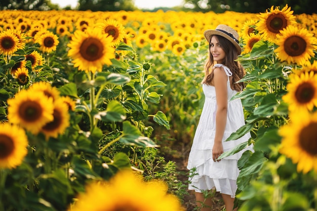 Lachende vrouw in een witte jurk lopen op een veld met zonnebloemen. ideaal voor reclame en fotozon schijnt helder en sappig