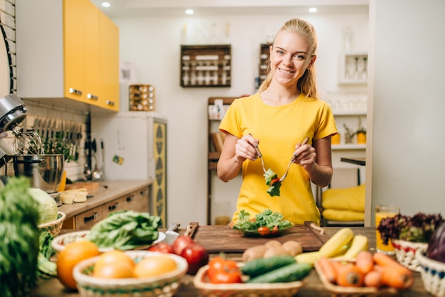 Lachende vrouw koken in de keuken, gezonde eco-voedselbereiding.