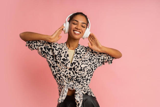 Lachende vrouw luisteren muziek door koptelefoon, poseren. Het dragen van stijlvolle blouse en leren rok.