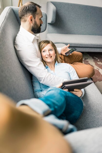 Lachende vrouw met tablet en man met mobiele telefoon op de bank