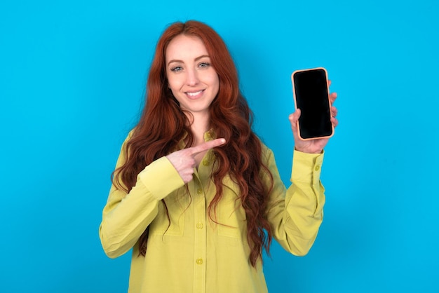 Lachende vrouw Mock up kopieer ruimte Wijzende wijsvinger op mobiele telefoon met leeg leeg scherm