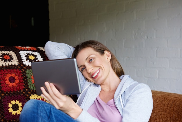 Lachende vrouw om thuis te zitten met een tablet